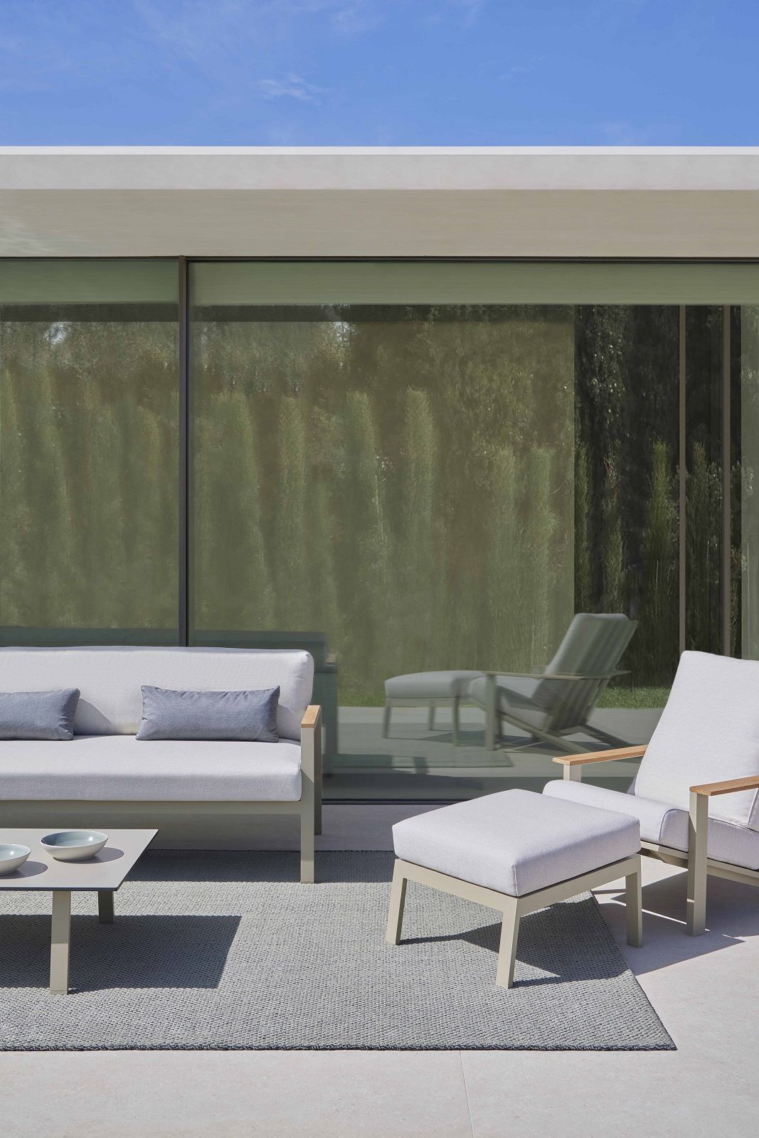 Grauer Saline Outdoor Teppich von Gan unter Gartenmöbeln auf einer Terrasse.