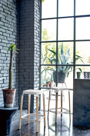 Zwei Steelwood Barhocker von Magis mit weißer Sitzfläche und Holzbeinen vor Fenster.