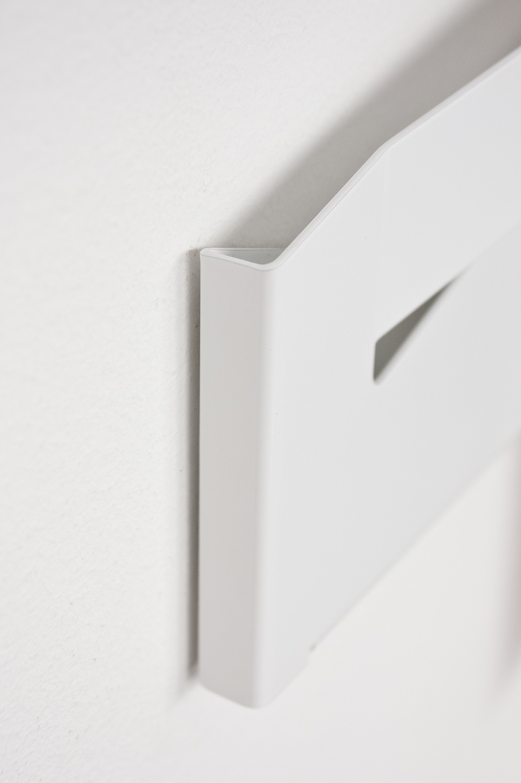 Detailaufnahme des weißen Mr. Magazinhalters von Müller Möbelwerkstätten an einer weißen Wand.