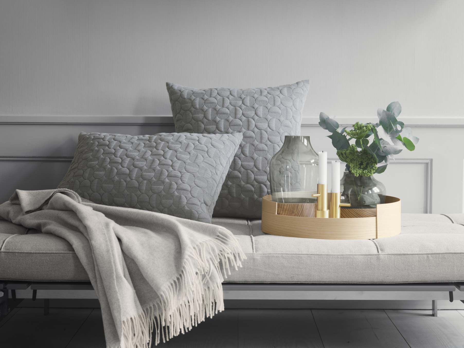 PK 80 Liege von Fritz Hansen mit Kissen, Decke und Dekoration in Grautönen.