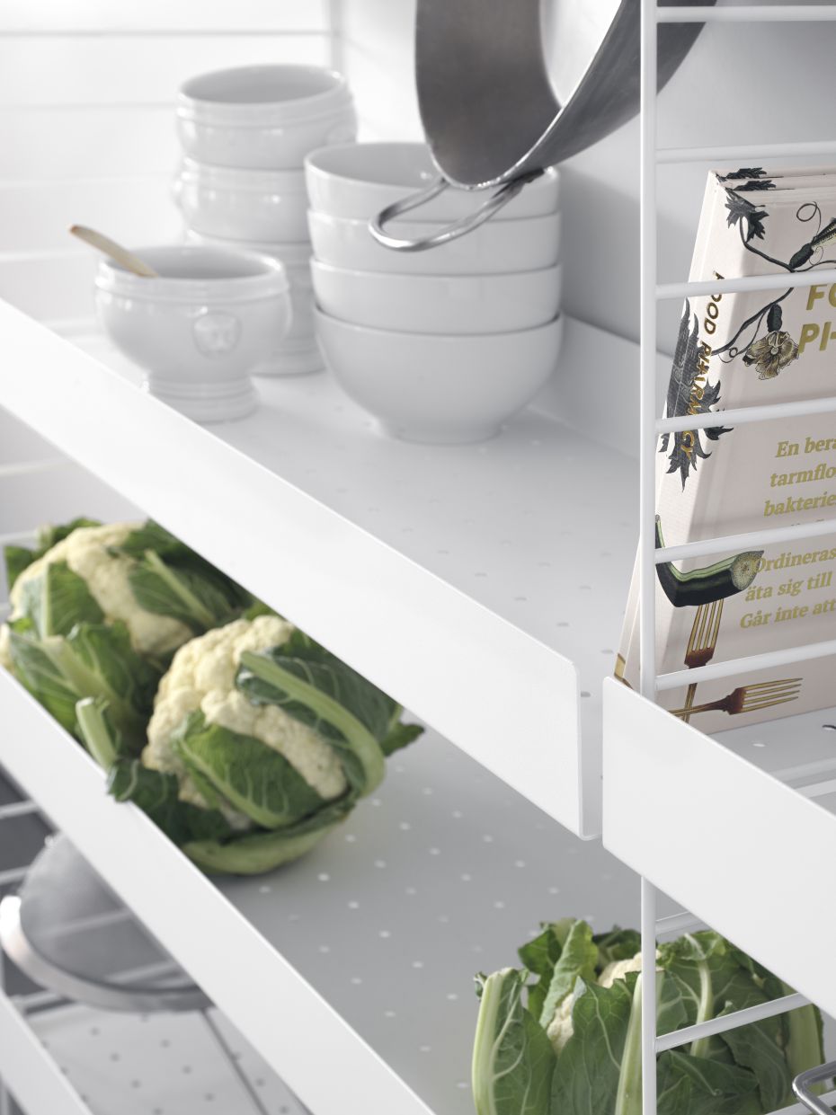 Weißer String Regalboden aus Metall (58 cm) mit hoher Kante, bestückt mit Geschirr und Gemüse.