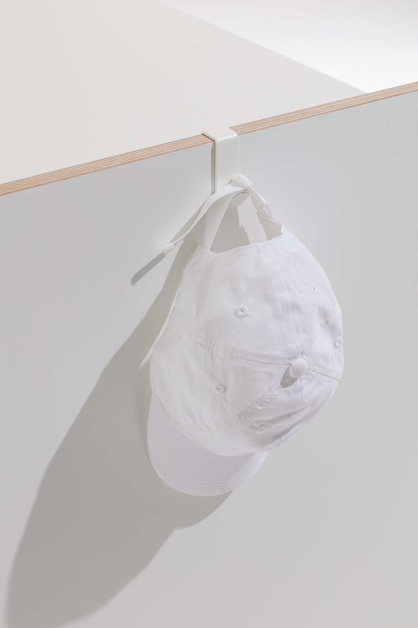 Weiße Kappe hängt an Flai Zubehör Kleiderhaken für Müller Möbelwerkstätten Sekretär, praktische Aufbewahrung.