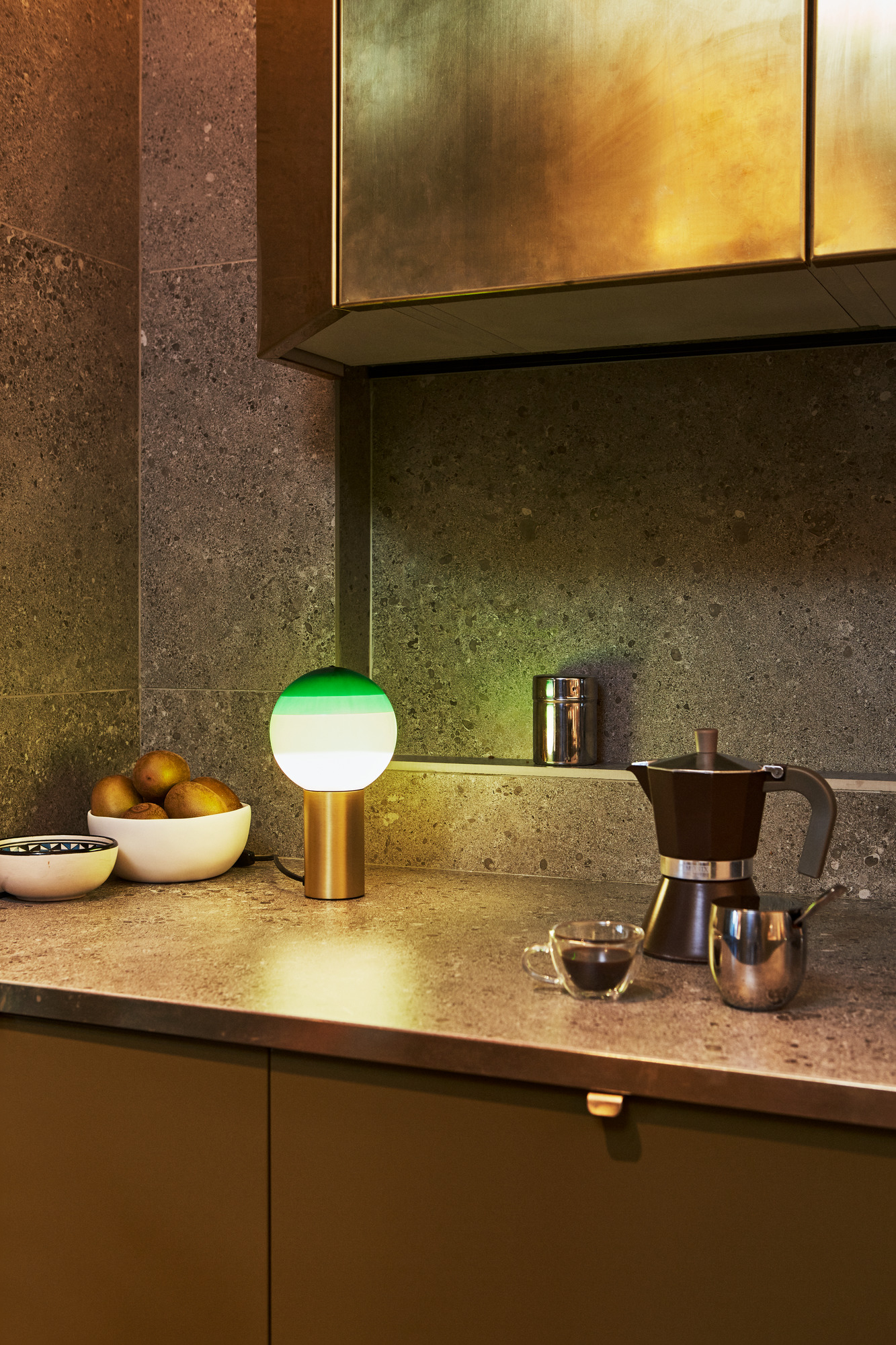 Dipping Light S LED Tischleuchte von Marset auf Küchentheke mit Kaffeekanne und Obstschale.