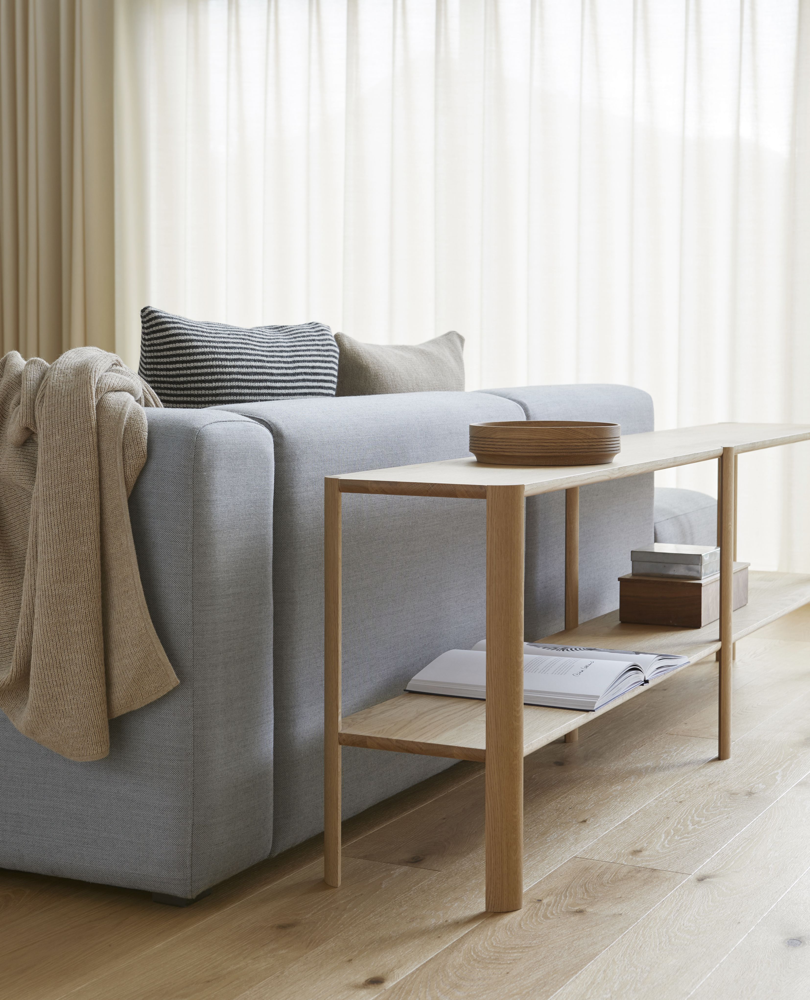 Leaf Regal 2x2 von Form & Refine aus Eiche, weiß geölt, neben einem Sofa.