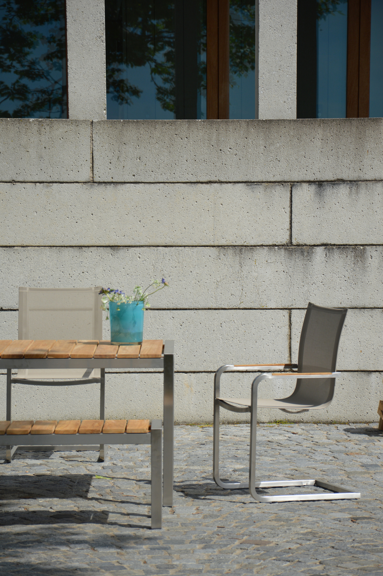 Moderner Jan Kurtz Tisch mit Holzplatte und Stahlgestell, ergänzt durch stilvollen Stuhl und blumengeschmückte Vase.