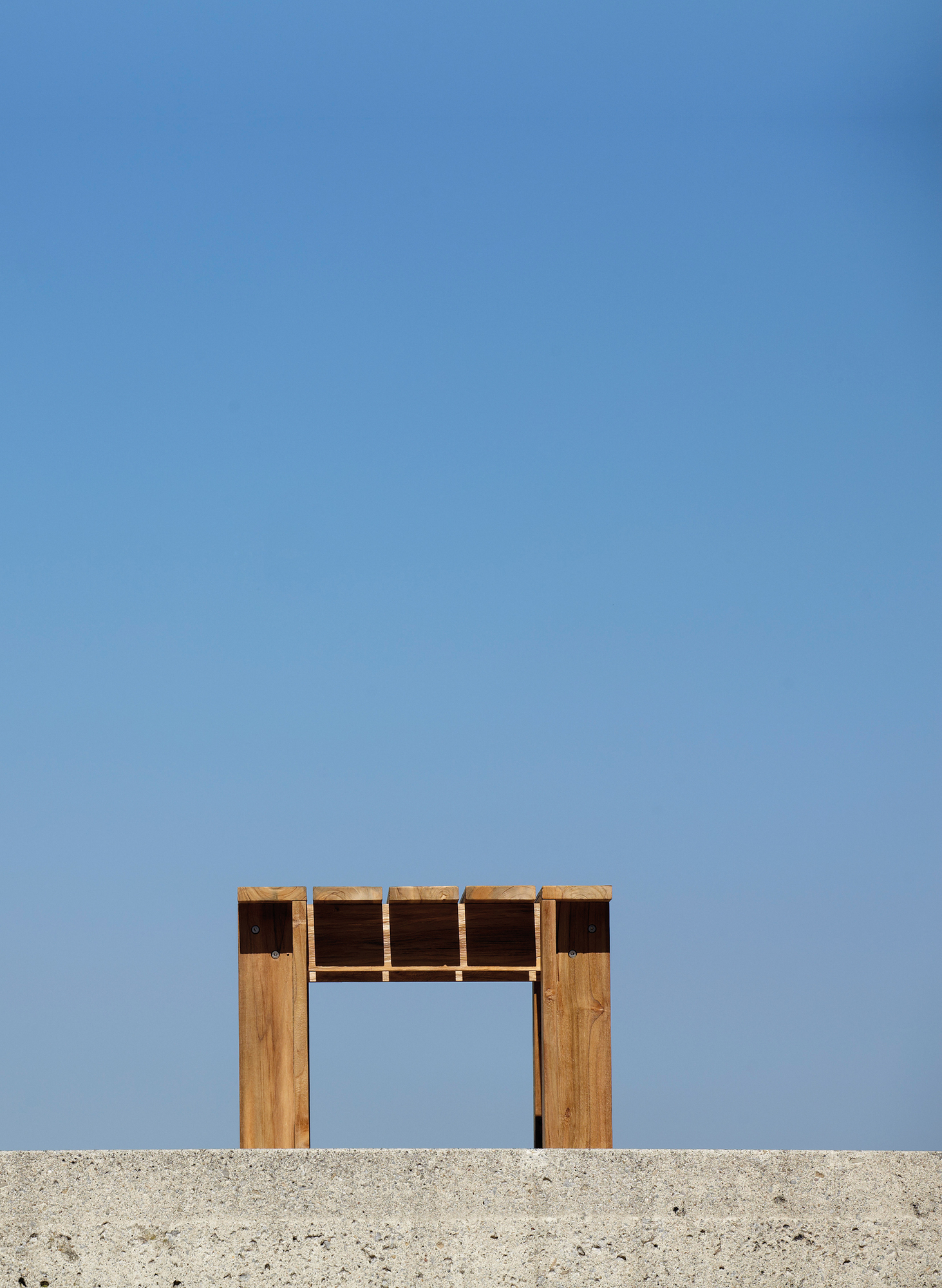 Jan Kurtz Batten Lounge Beistelltisch Natur, minimalistischer Holztisch vor blauem Himmel. Outdoor Möbel.