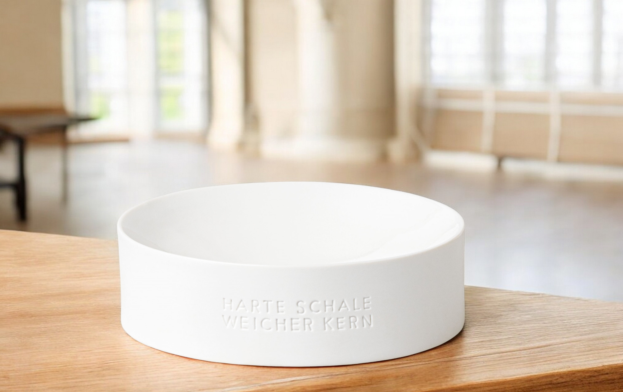 Weiße Nusschale "Harte Schale weicher Kern" von Räder auf einem Holztisch, minimalistisches Design.