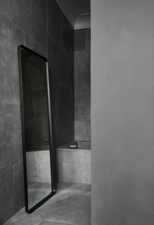 Norm Floor Mirror von Audo, ein großer, schwarzer Standspiegel im modernen Badezimmer.