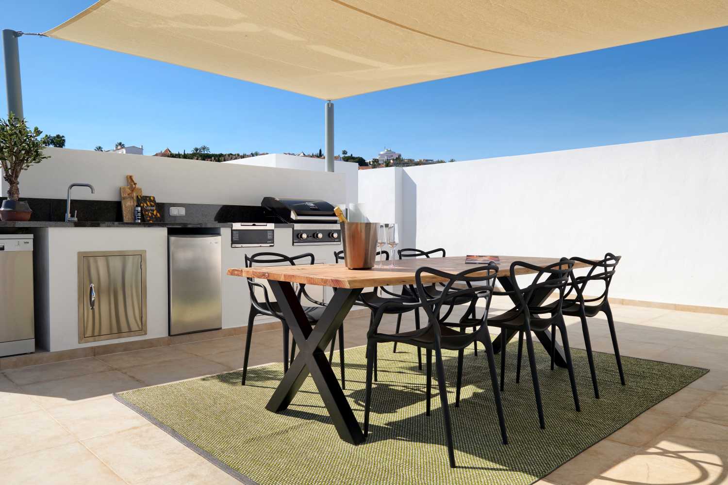 Senffarbener Effi Kunststoffteppich von Pappelina (230x320 cm) unter Esstisch im Außenbereich. Wetterfester Teppich für Terrasse.