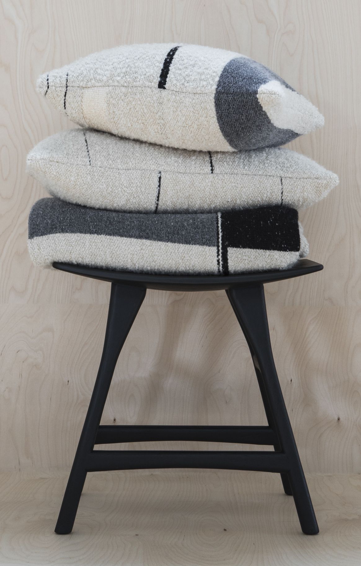 Osso Stuhl von Ethnicraft aus schwarzem Eichenholz mit dekorativen Kissen in Grau und Weiß.