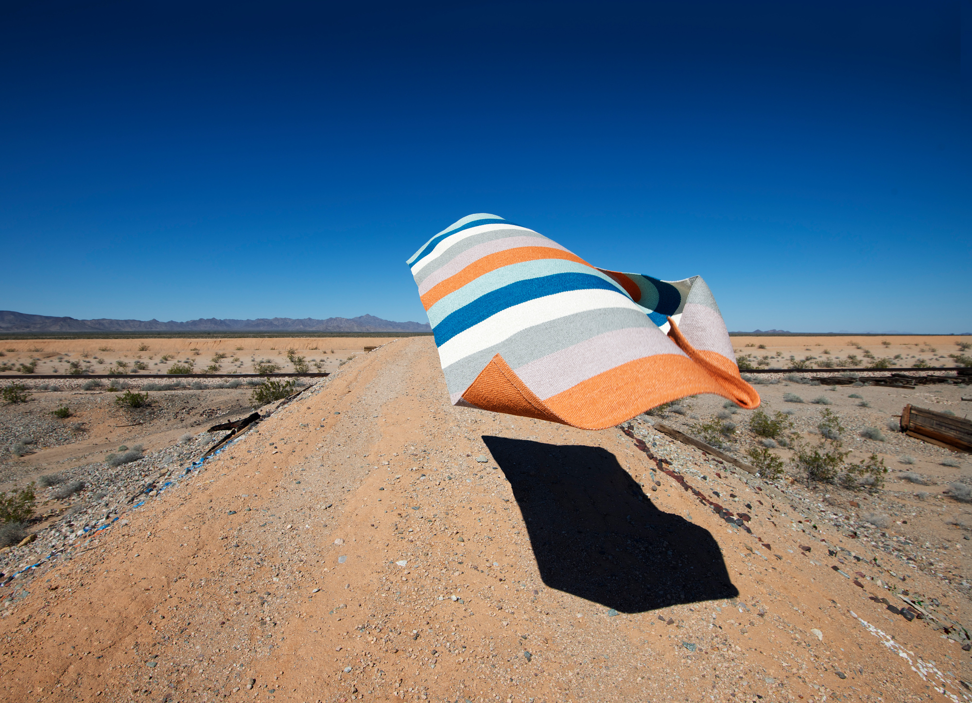 Muster des Molly Kunststoffteppichs von Pappelina, gestreift in Orange, Blau und Weiß.