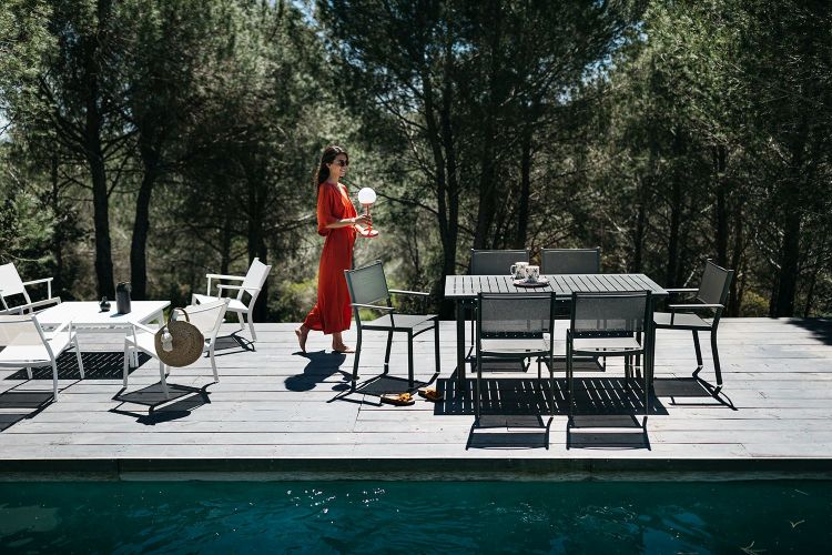 Costa Tisch von Fermob: Moderner Outdoor-Esstisch mit Stühlen auf einer Holzterrasse am Pool.