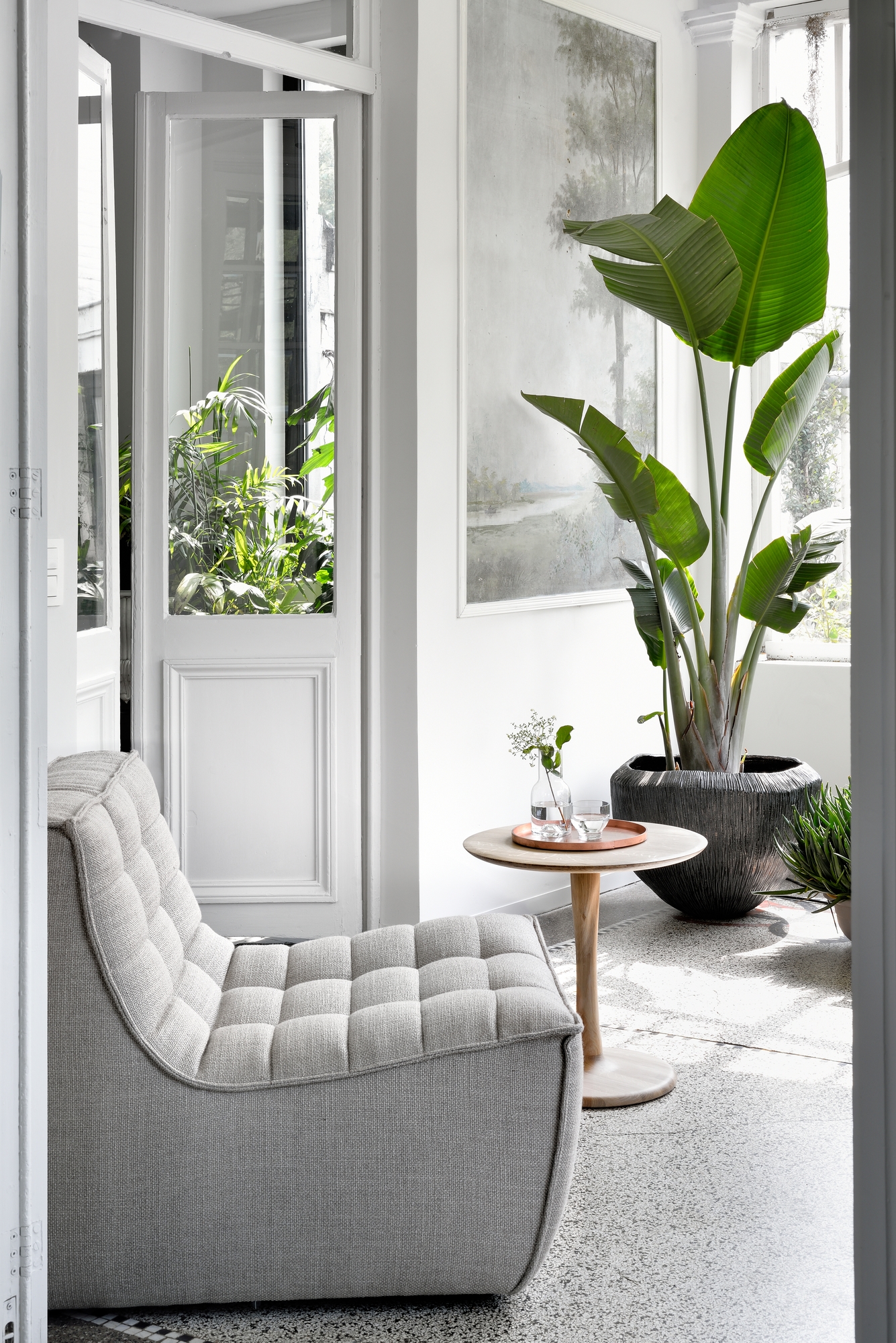 Heller Raum mit Sessel N701 von Ethnicraft, Beistelltisch, Pflanze und viel Tageslicht.