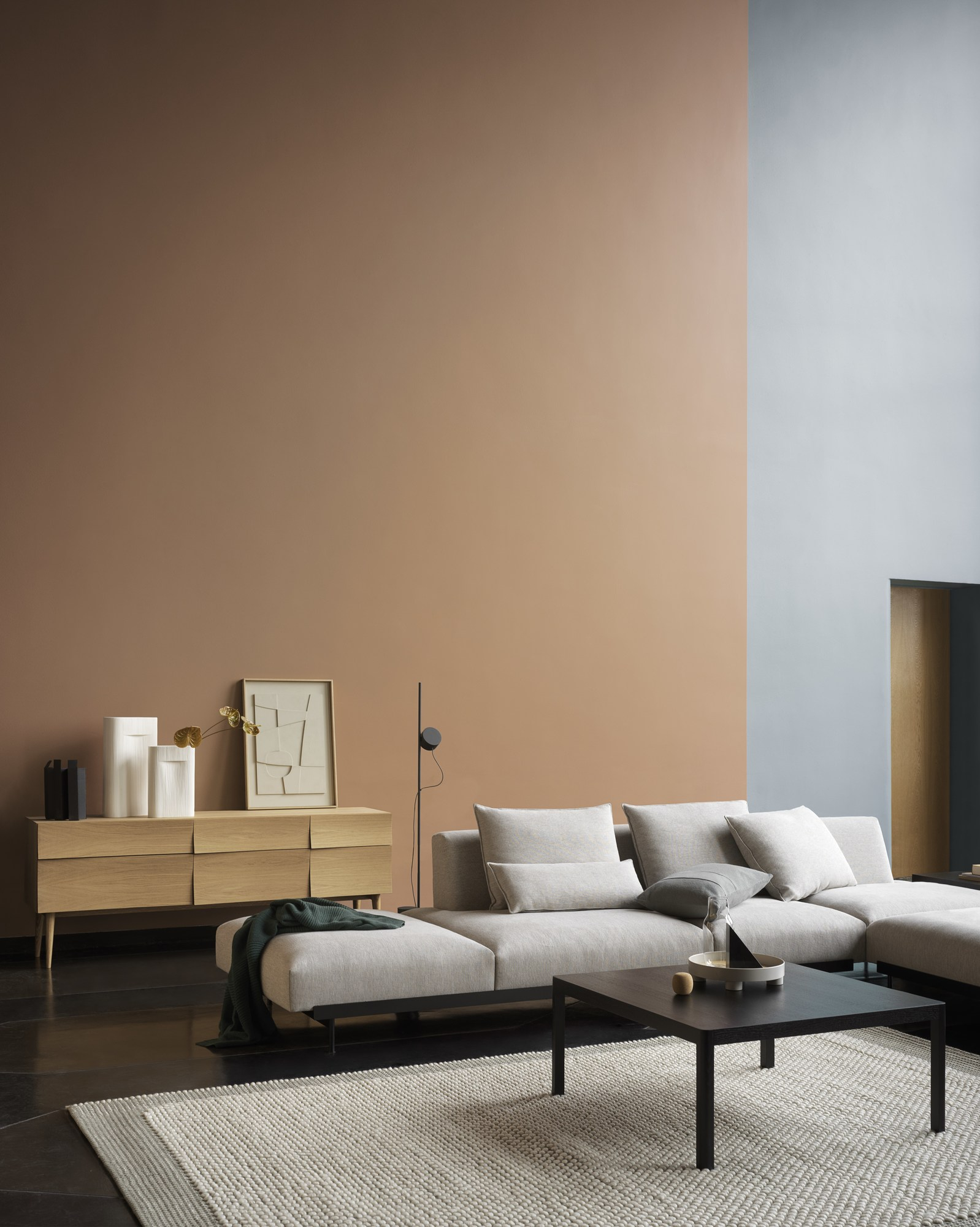 Wohnzimmer-Szene mit Muuto Reflect Sideboard aus Eiche, Sofa, Teppich und Dekoration.