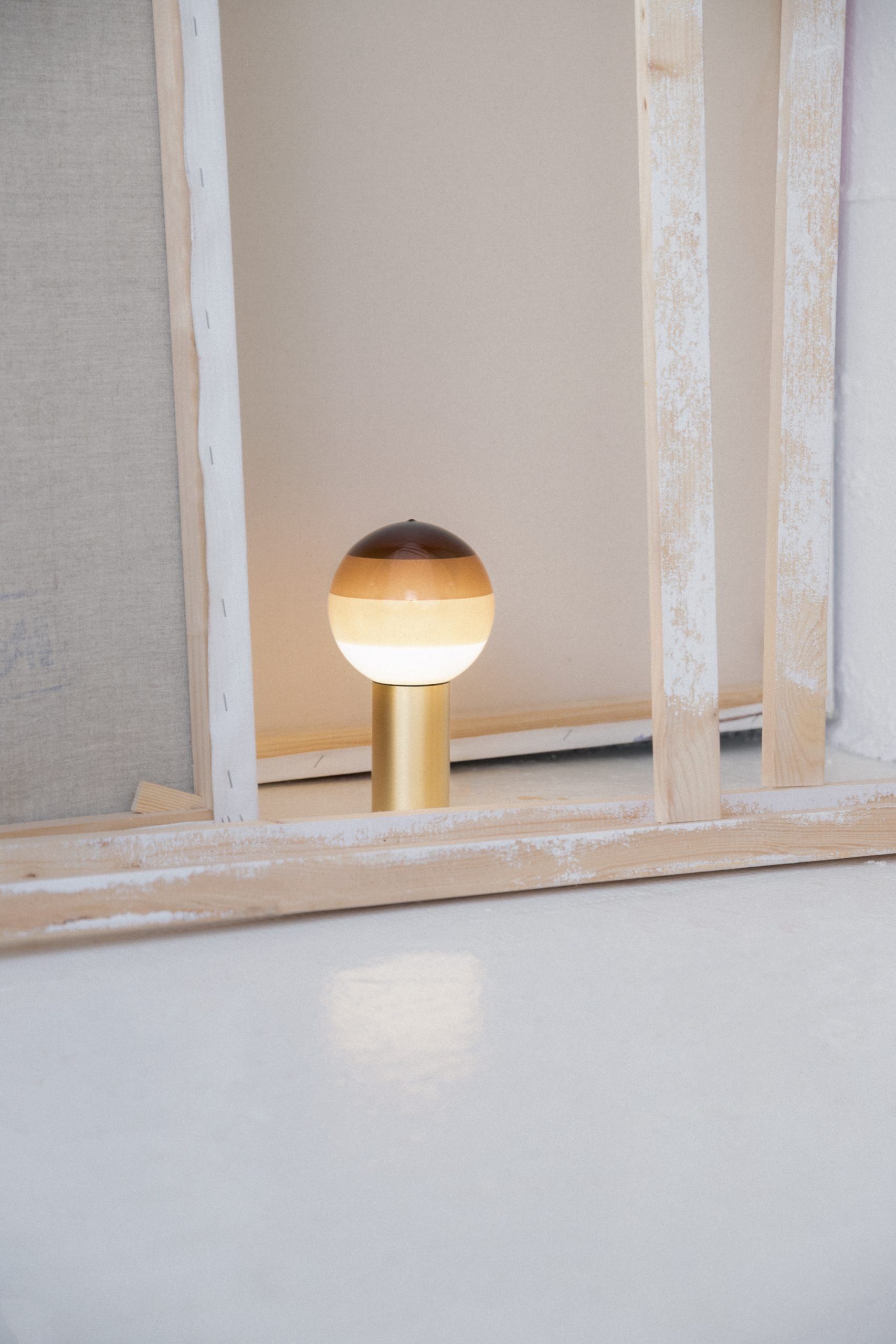 Nahaufnahme der Marset Dipping Light S LED Tischleuchte mit goldenem Fuß und farbigem Glasschirm.