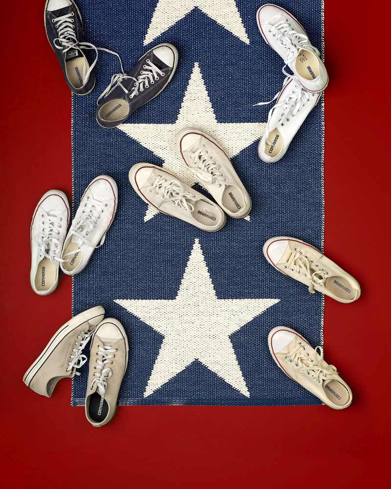 Viggo One Pappelina Kunststoffteppich Schwarz, 70x250 cm, mit Sternmuster und verschiedenen Converse Schuhen darauf.