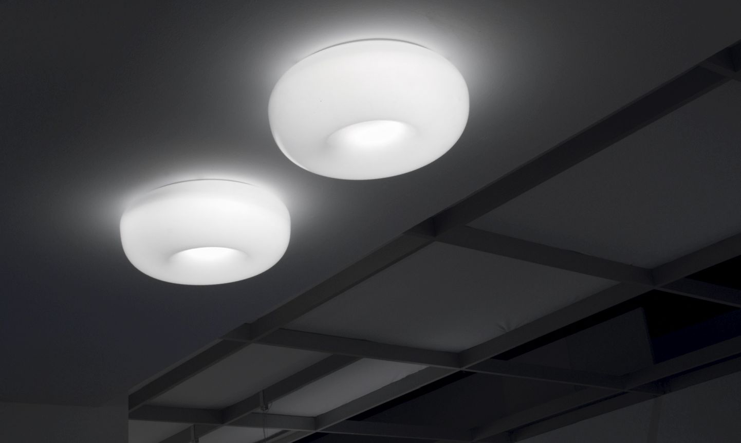 Zwei weiße Pouff Deckenleuchten von Martinelli Luce an einer dunklen Decke.