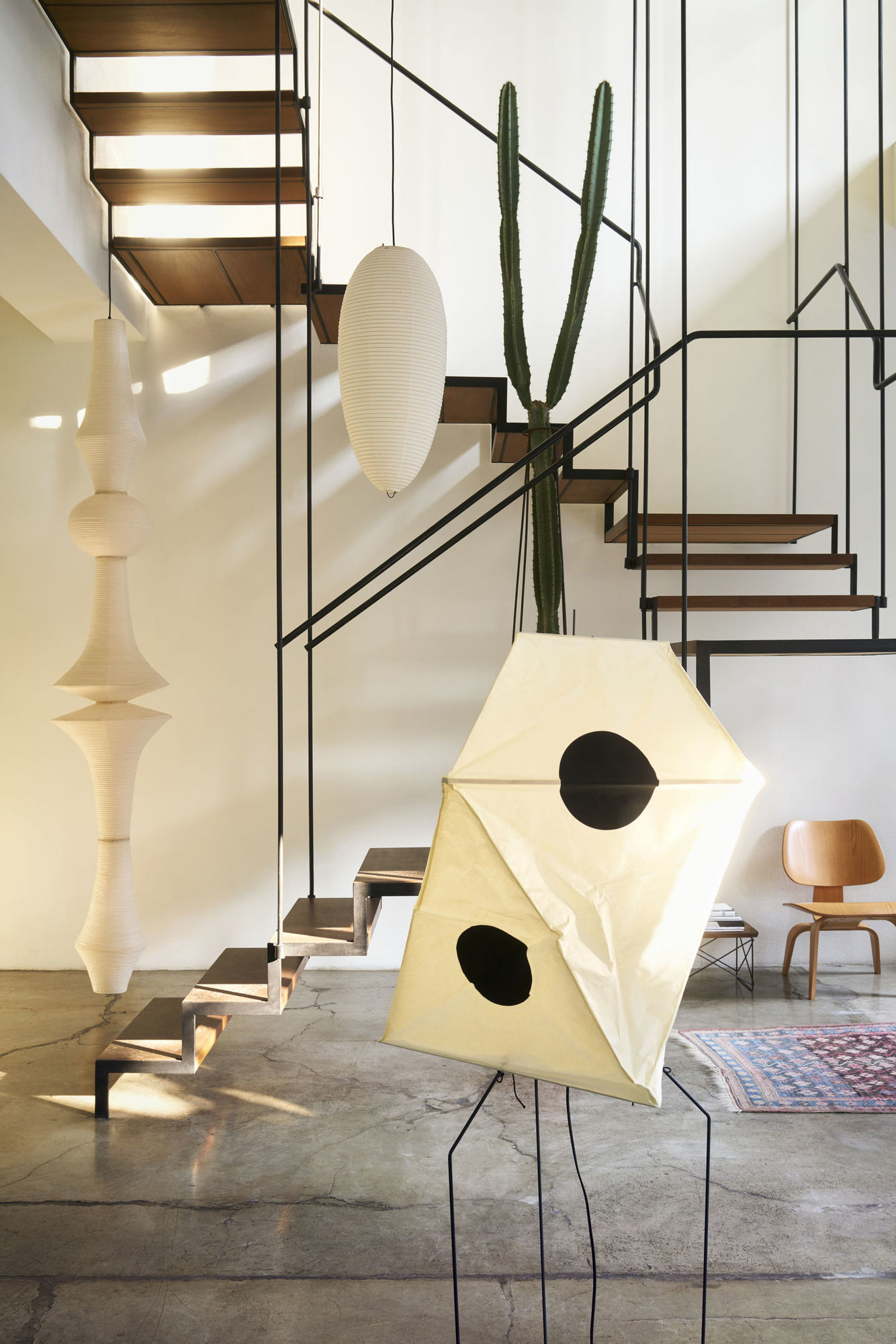 Vitra Plywood Group LCW Stuhl aus Holz in modernem Wohnraum mit Treppe und Lampen.