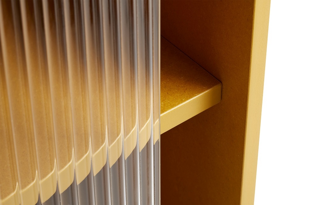 Detailaufnahme: Gelber Hay Schrank mit geriffelter Glastür und Innenregal. Moderner Stauraum.