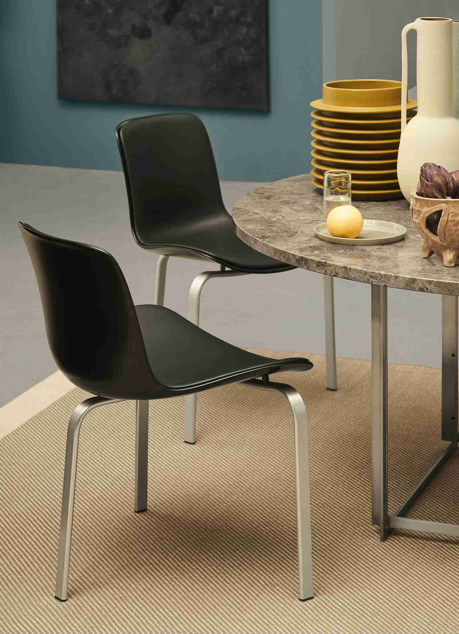 Zwei schwarze PK8 Stühle von Fritz Hansen an einem runden Marmortisch. Designermöbel für Esszimmer.