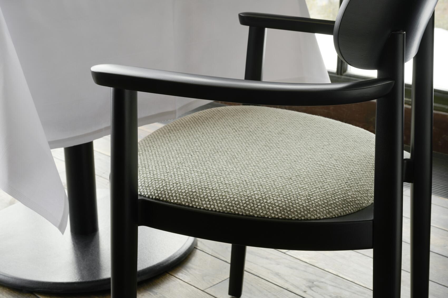 Detailaufnahme: Schwarzer 118 SPFV Thonet Holzstuhl mit Armlehnen und hellgrauem Stoffbezug.