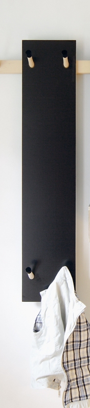 Schwarze Kindergarderobe von Moormann mit Holzhaken und hängender Kinderkleidung an einer weißen Wand.