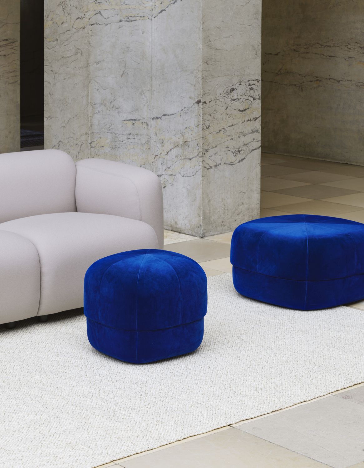 Zwei blaue Circus Poufs von Normann Copenhagen auf einem Teppich, neben einem Sofa.