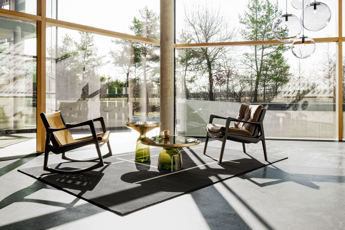 Moderner Wohnraum mit ClassiCon Monolith Teppich, 200x300cm, grau mit Linienmuster, Sesseln und Beistelltischen.
