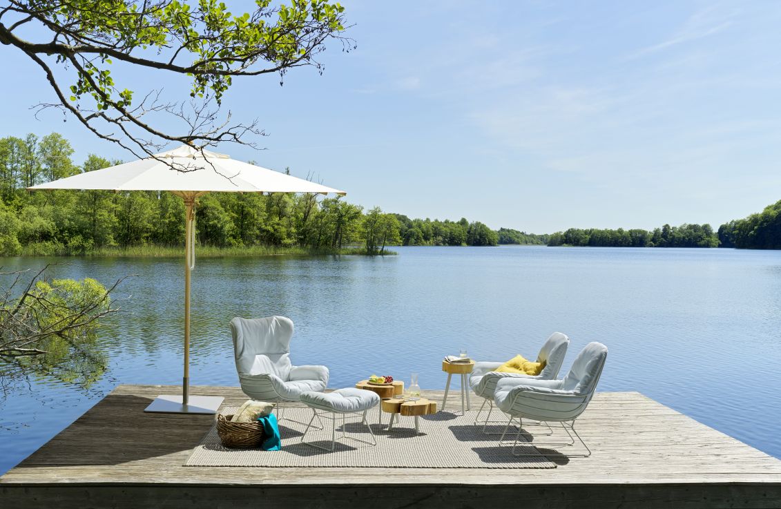 Leyasol Ottoman Outdoor: Elegante Gartenmöbel auf Holzsteg am See mit Sonnenschirm. Freifrau Manufaktur Design.