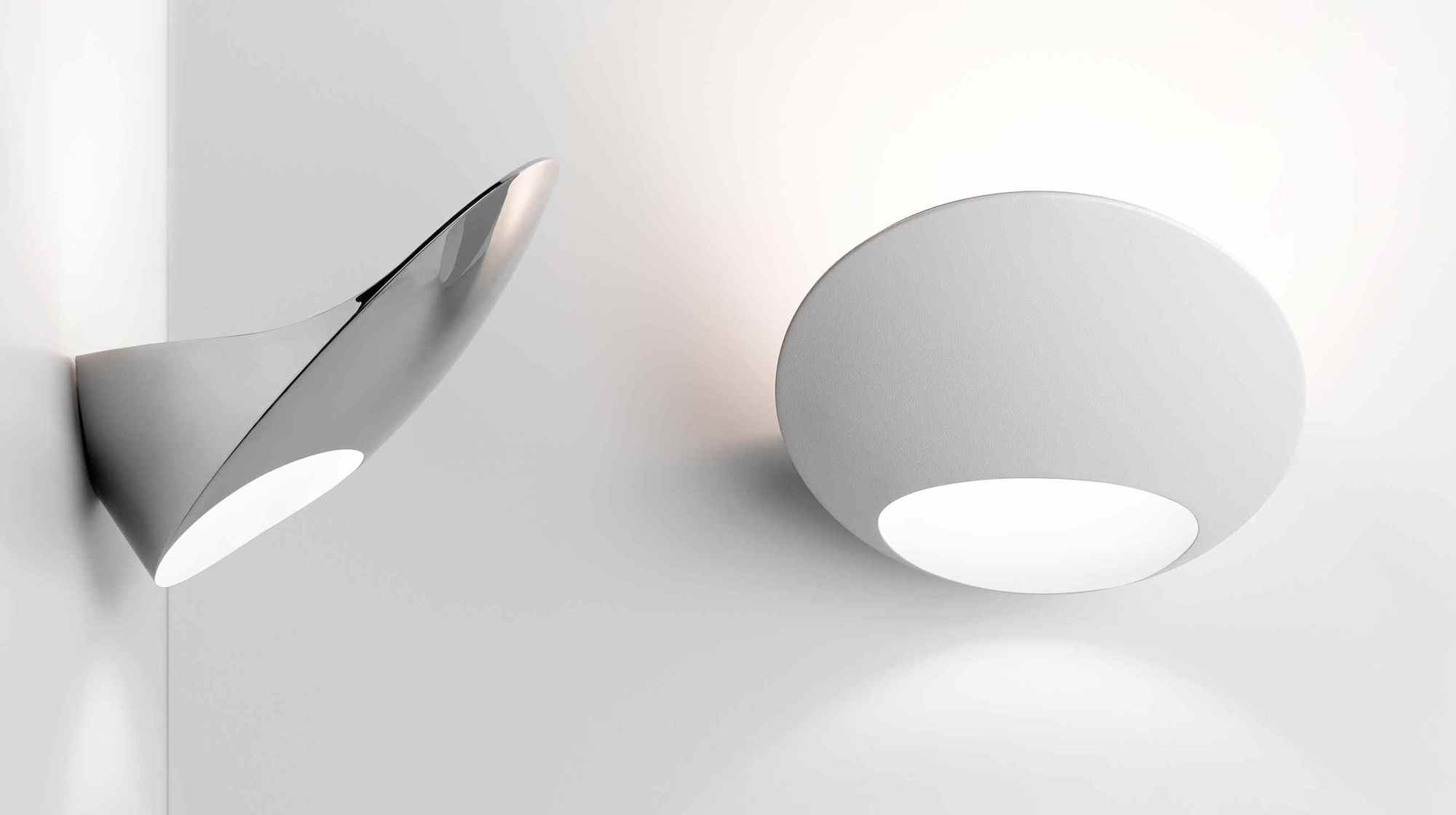 Zwei moderne Wandleuchten, darunter die D90 Garbi, in Weiß und Silber an einer weißen Wand.