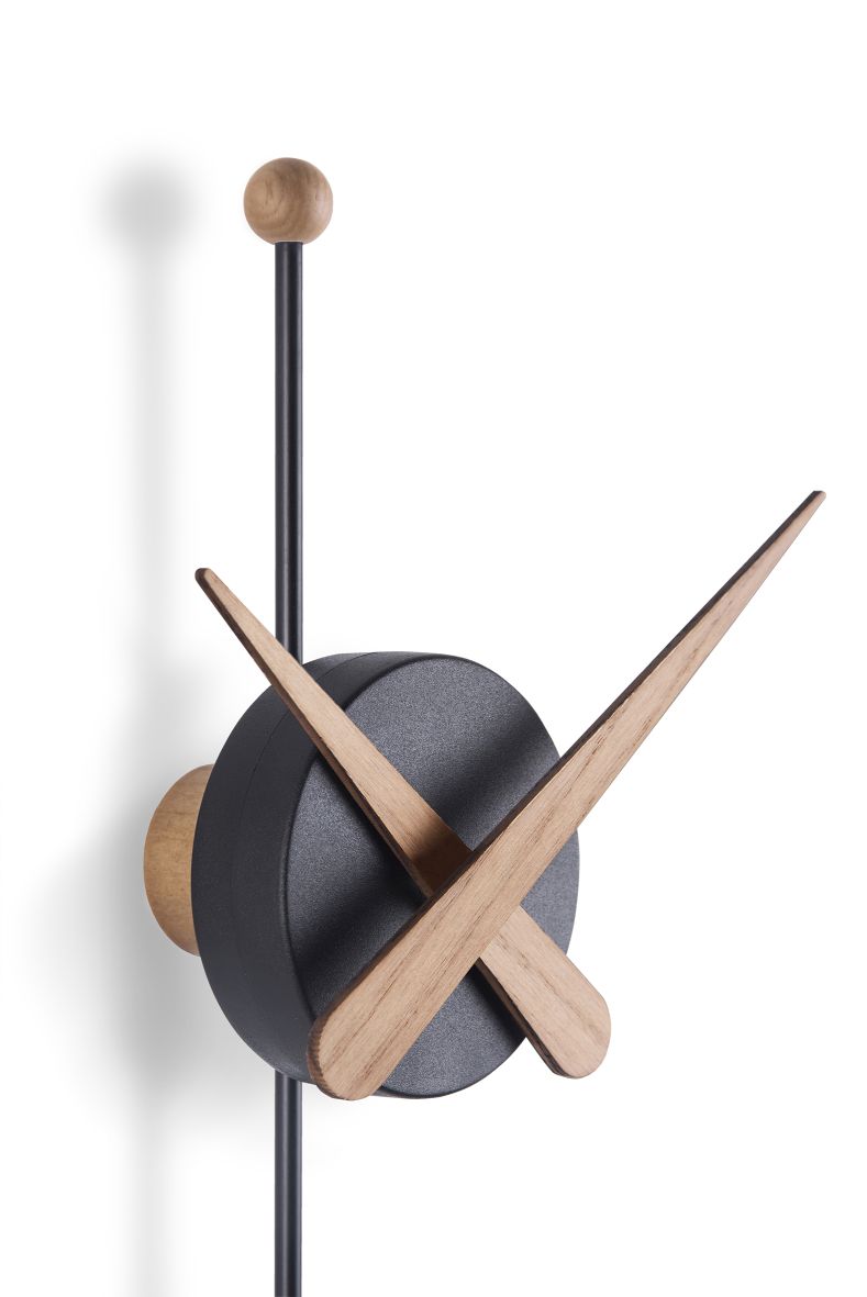 Detailaufnahme der modernen Punta Wanduhr von Nomon mit schwarzen Ziffernblatt und Holzzeigern.