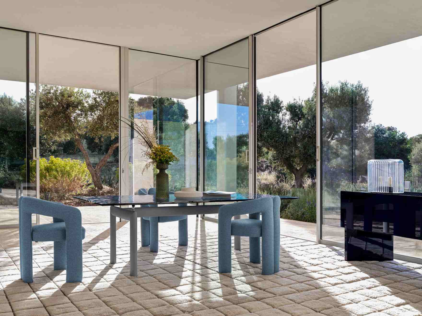 LC6 Table tube d´avion Esstisch Cassina mit blauen Stühlen in modernem, lichtdurchflutetem Raum. Designmöbel für Esszimmer.