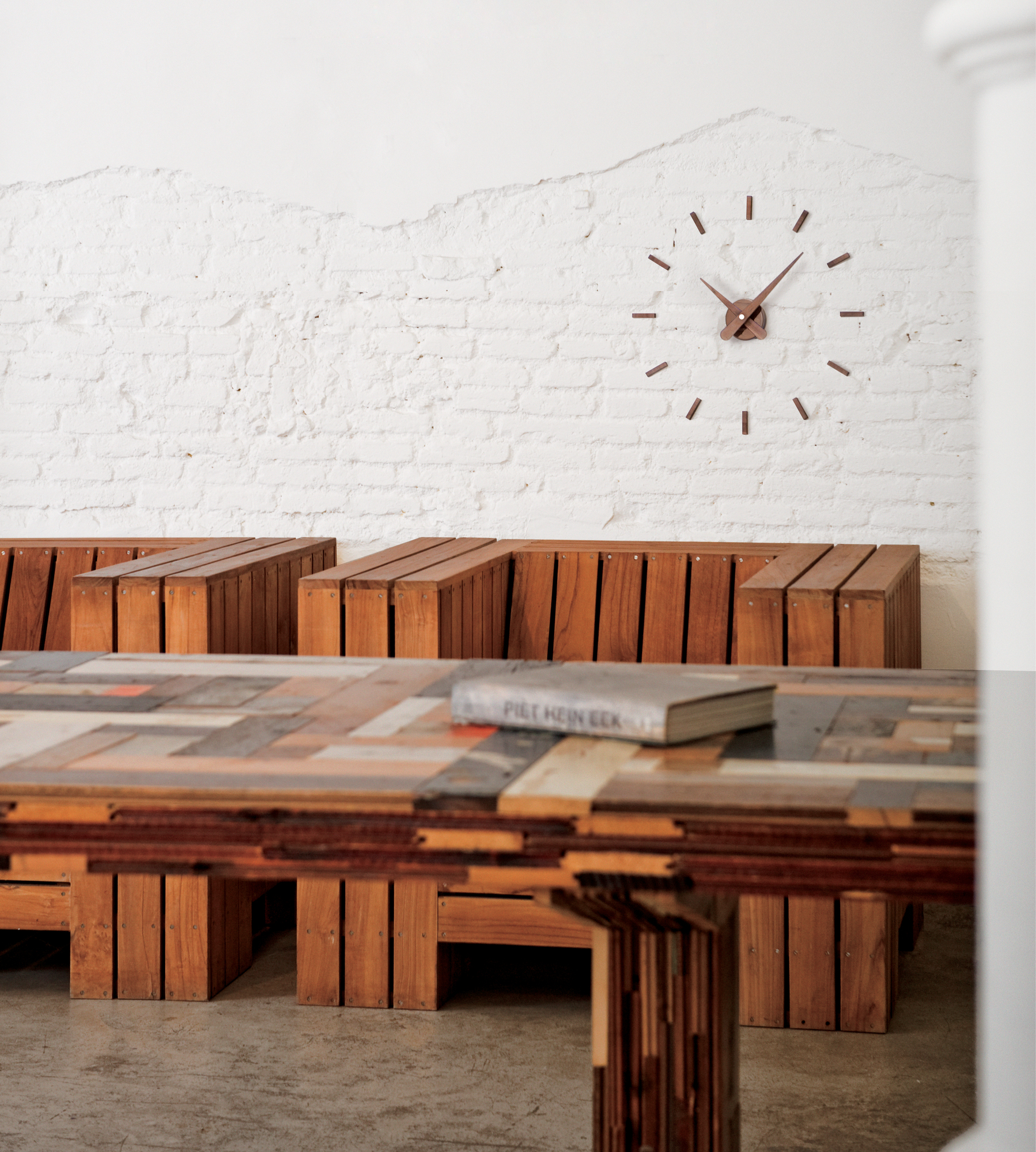 Sunset N Wanduhr von nomon an einer weißen Ziegelwand, minimalistisches Design, braune Zeiger und Indizes.