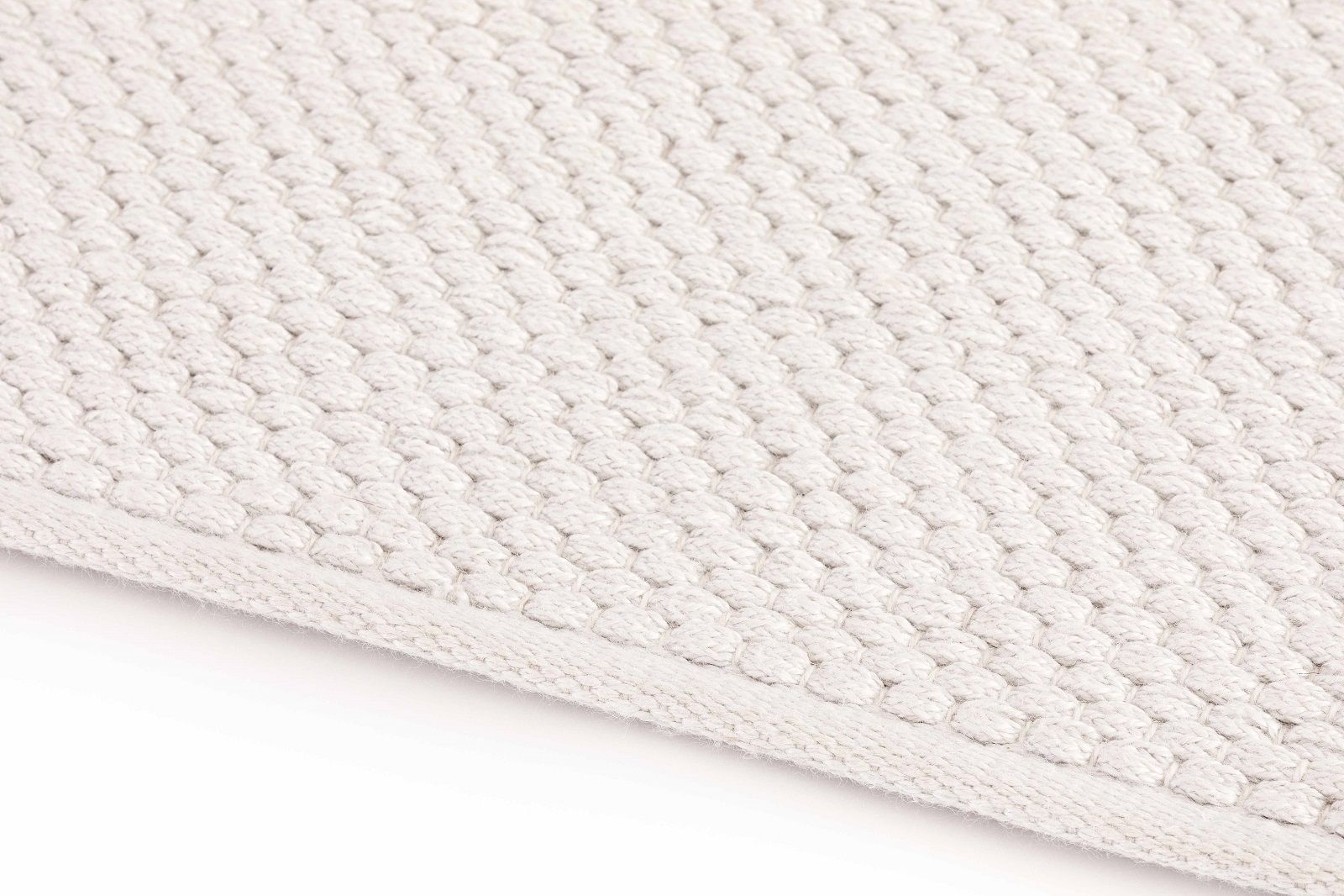 Detailaufnahme des weißen Mangas Outdoor Teppichs mit gewebter Textur für Terrasse und Balkon.