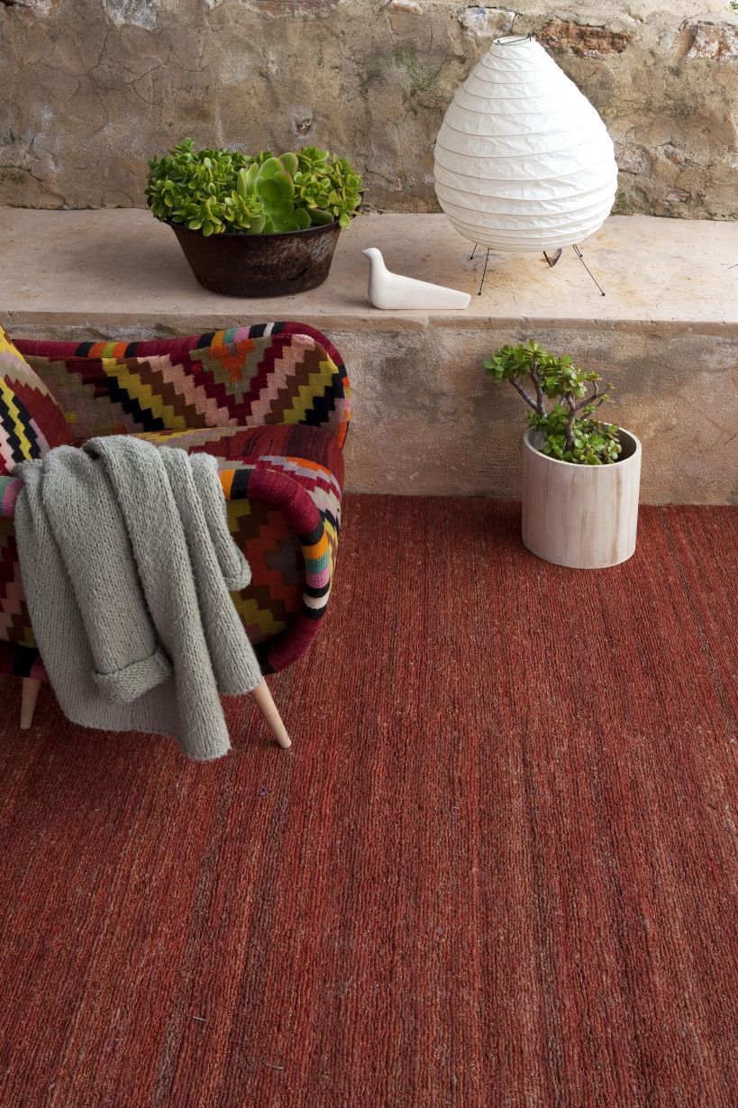 Nanimarquina Earth Rug Teppich Khaki, 250x350cm. Detailaufnahme des Teppichs mit Sessel und Dekoration.