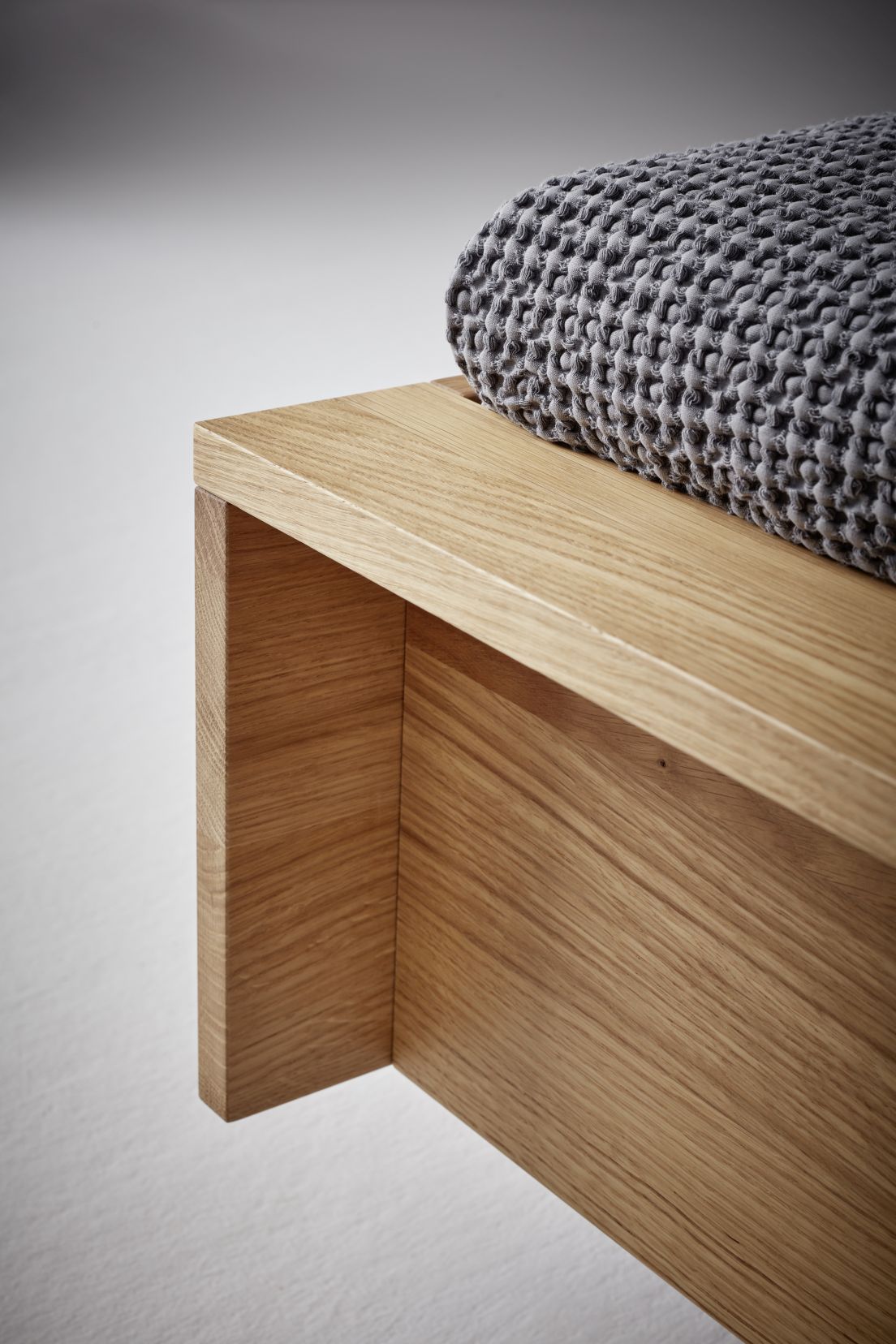 Detailaufnahme vom Flai Bett Eiche von Müller Möbelwerkstätten mit grauer Tagesdecke.