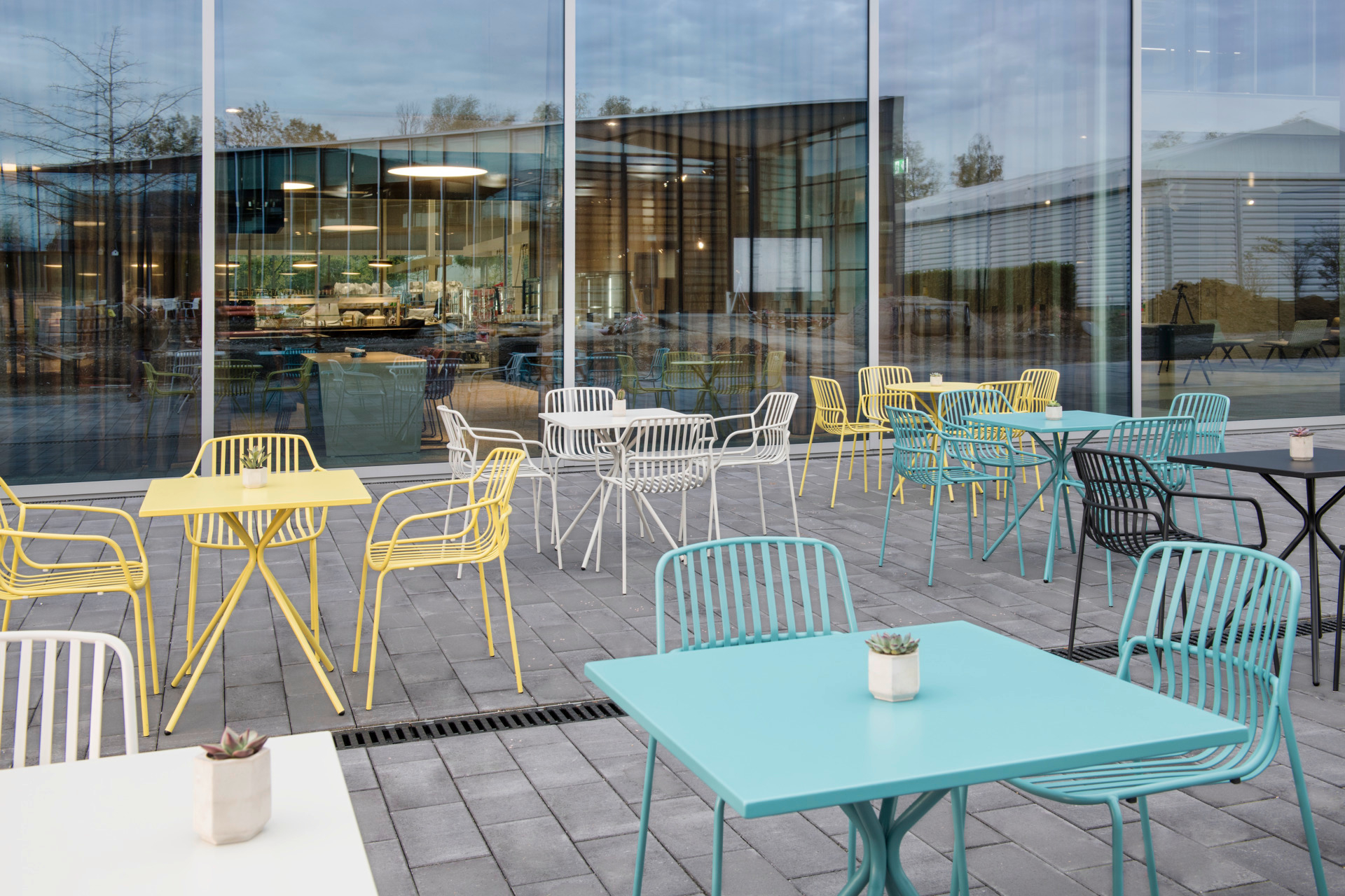 Brunner Crona Steel Bistrotische quadratisch Outdoor in verschiedenen Farben auf einer Terrasse.