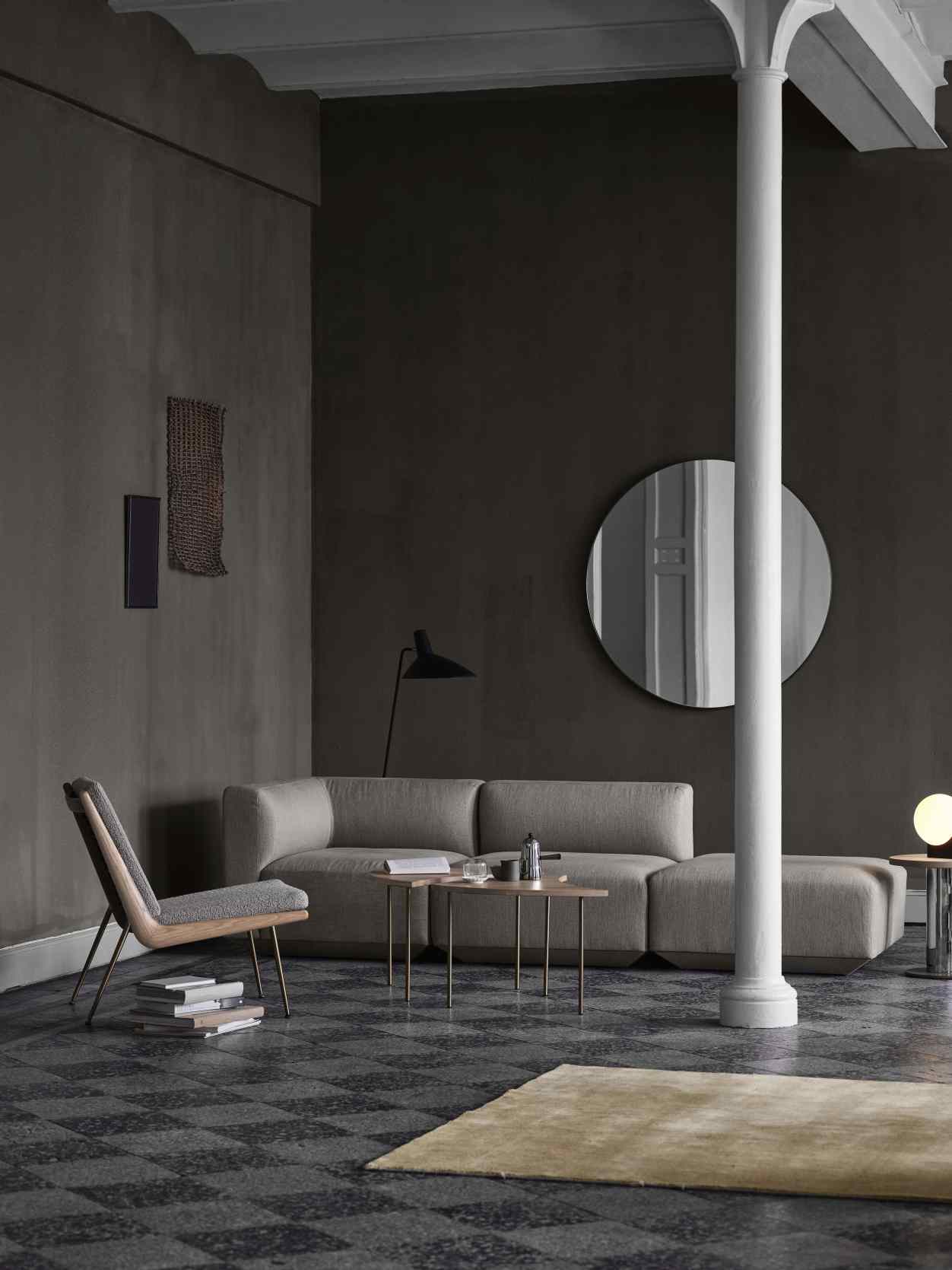 Wohnzimmer mit AndTradition Spiegel, rund, Durchmesser 115 cm, an dunkler Wand. Dekorative Wandspiegel für modernes Wohnambiente.