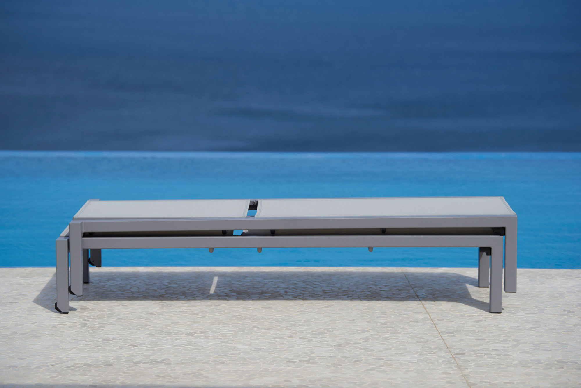 Nahaufnahme einer Cane-Line Sonnenliege ohne Kissen, hellgraues Gestell, für den Outdoor-Bereich.