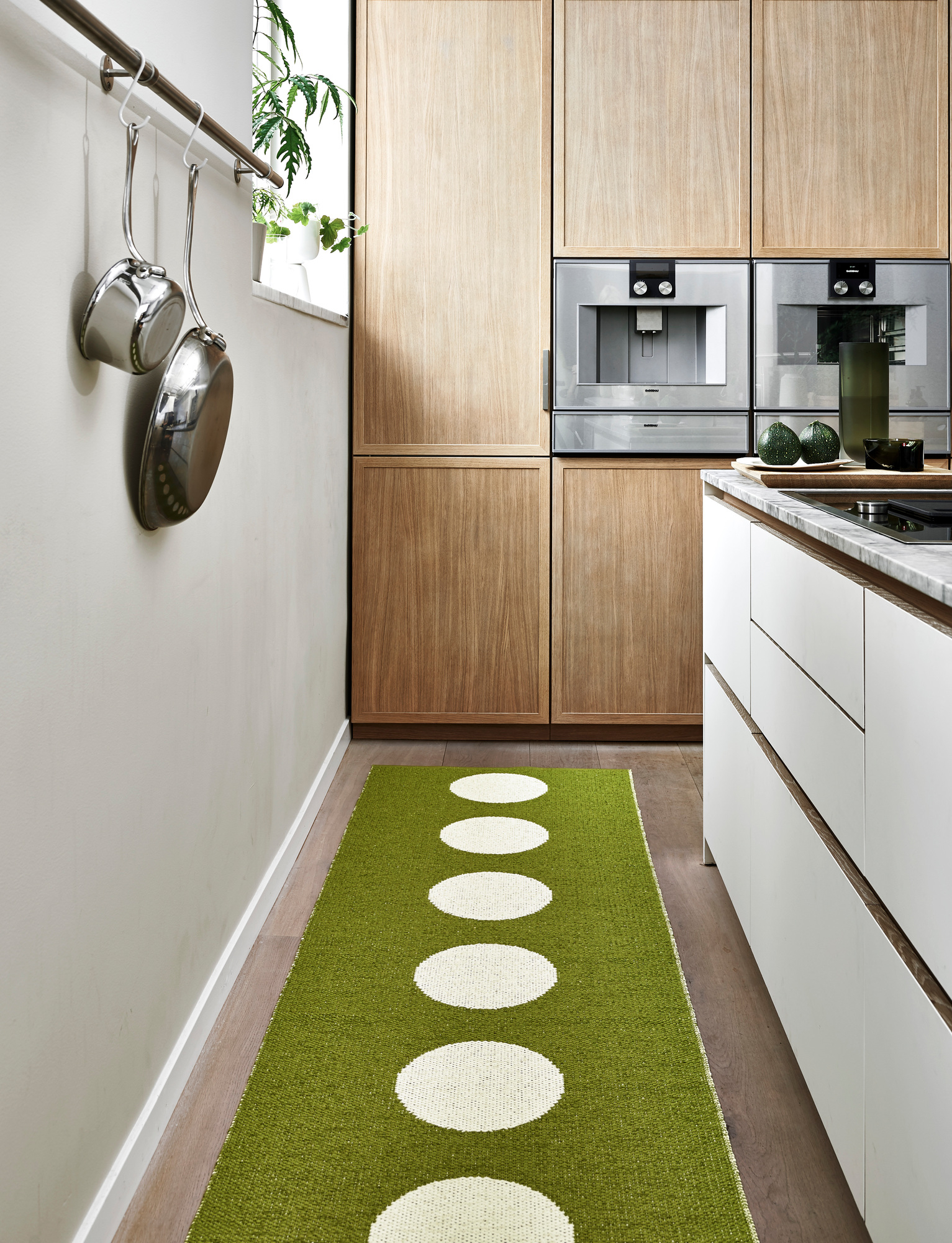 Vera Kunststoffteppich von Pappelina, 70x300 cm, in grüner Farbe mit weißen Kreisen im Küchenbereich.