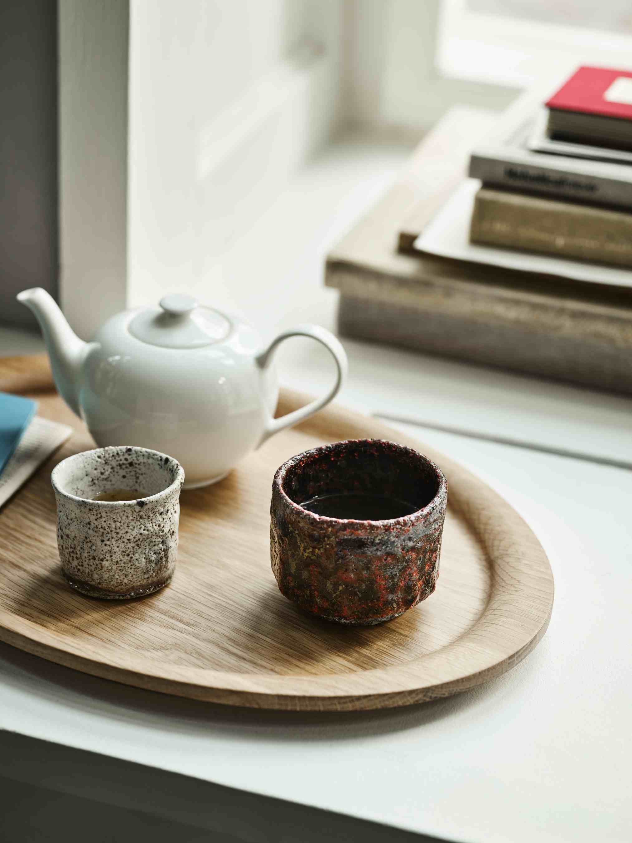 AndTradition Tray SC64-SC65: Ovales Eichenholztablett mit Teekanne und zwei Keramiktassen am Fenster.