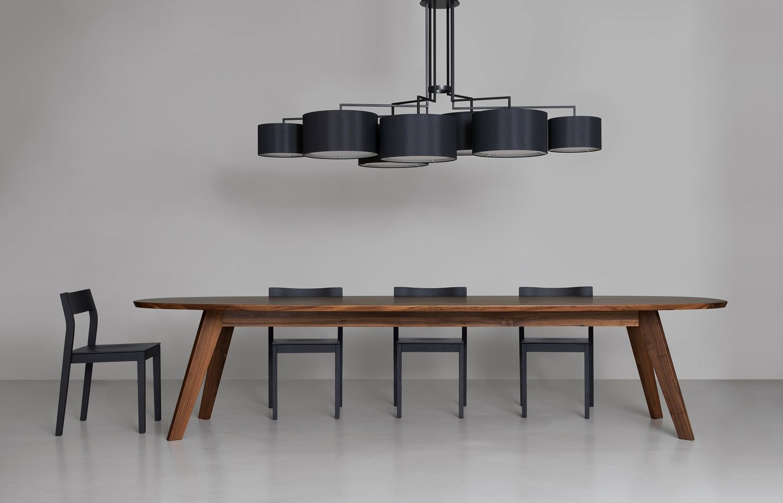 NOON Deckenleuchte in Weiß über Esstisch mit schwarzen Stühlen, modernes Lampendesign.