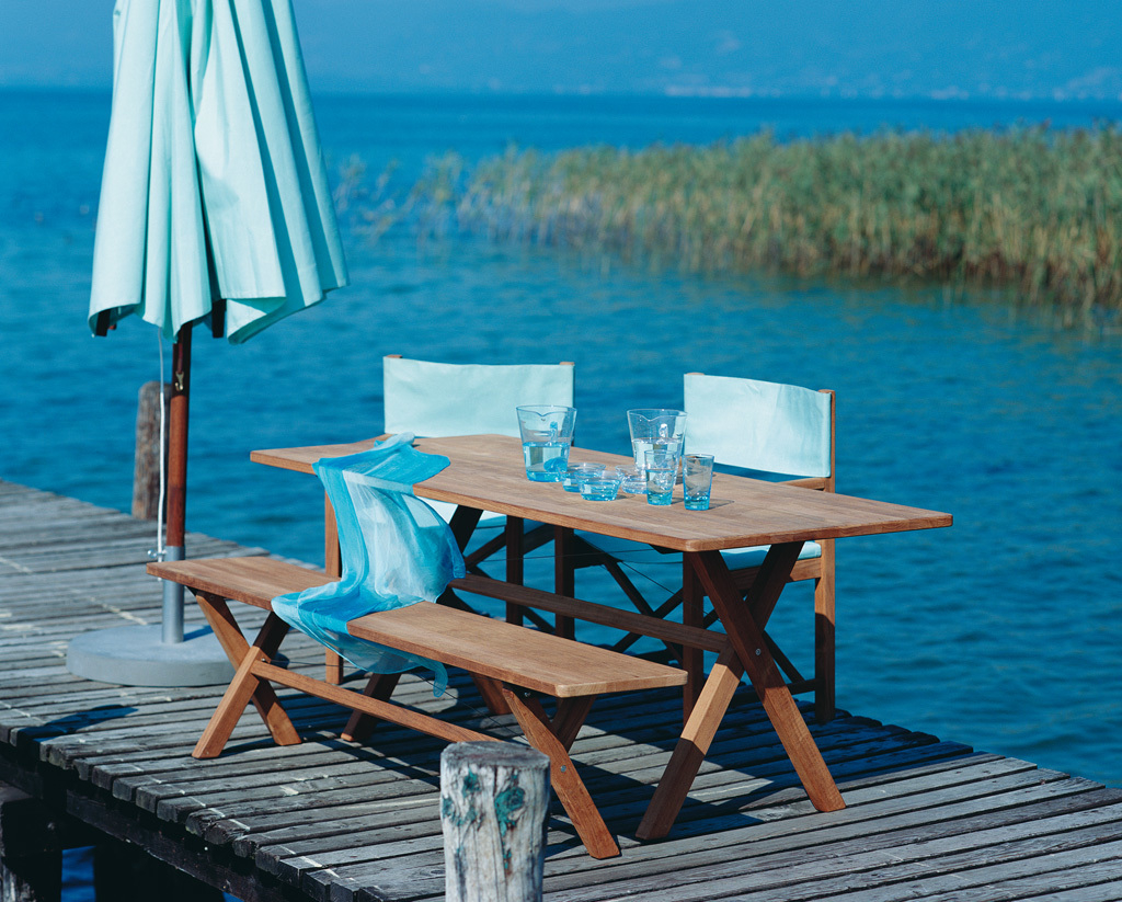 Cross Tisch klappbar von Weishäupl auf Holzsteg am See, mit Stühlen und Sonnenschirm.