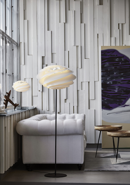 Weiße Swirl Stehleuchte von Le Klint im modernen Wohnzimmer mit Sofa und Kunst.