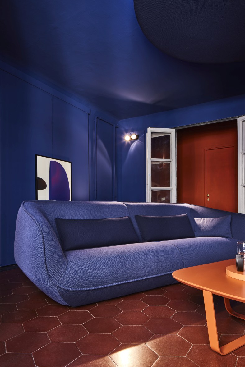 Blaues Nook Sofa von Cor mit Kissen in modernem Wohnzimmer mit Terrakottafliesen.