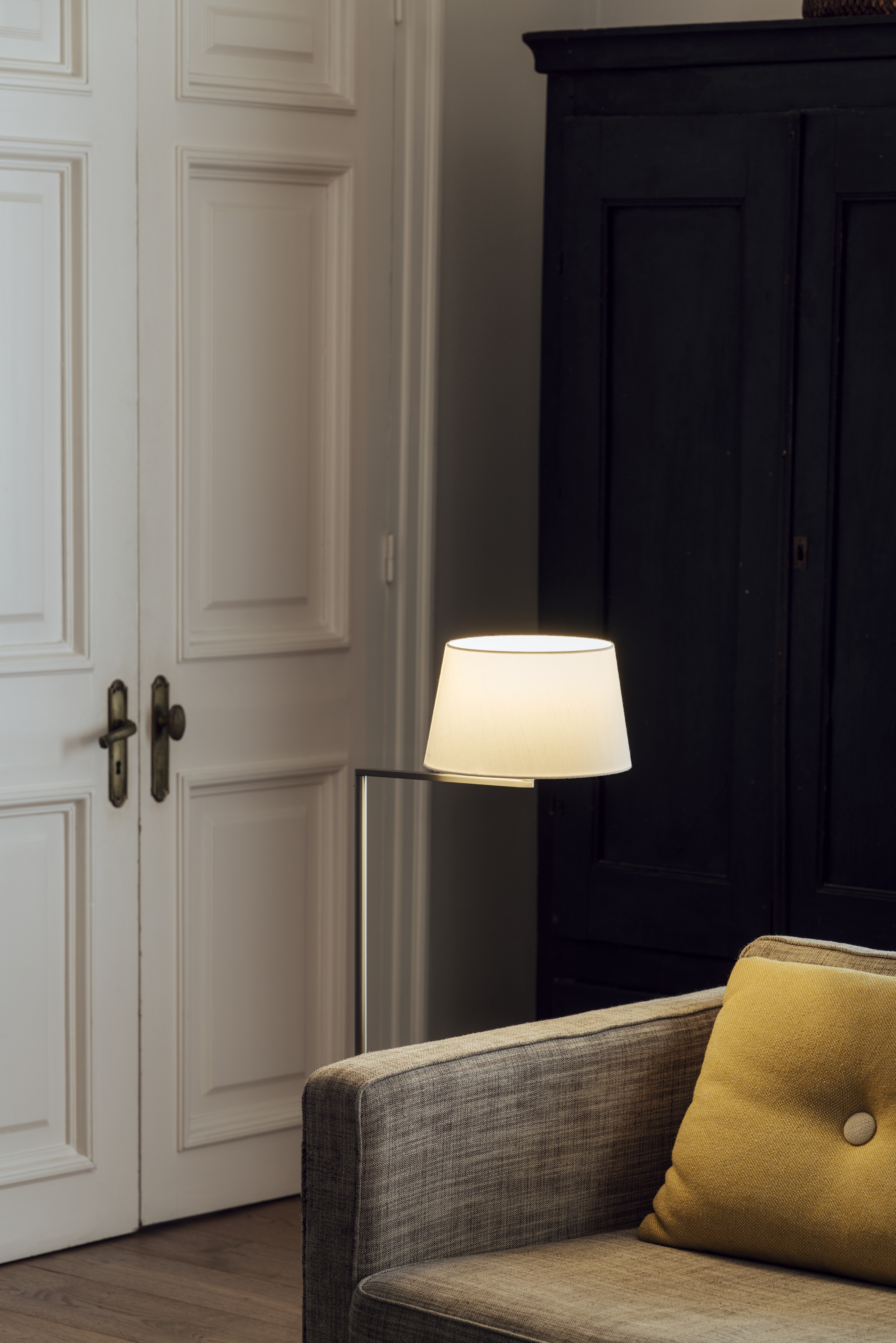 Americana Stehleuchte von Santa & Cole neben Sofa und Schrank in einem Wohnraum.