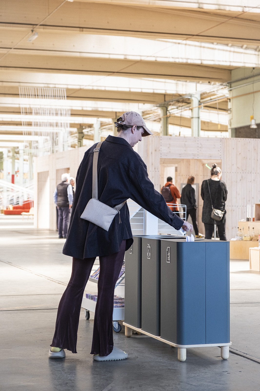 Person wirft Papier in Arkad Bin Mülleimer zur Mülltrennung von Mizetto. Nachhaltige Abfallbehälter für Büro.