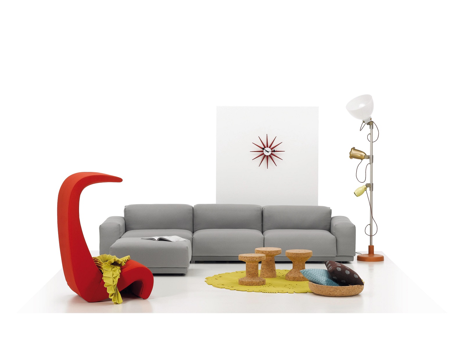 Wohnzimmer mit grauem Sofa, rotem Sessel und drei Vitra Cork Family Tischen aus Kork.