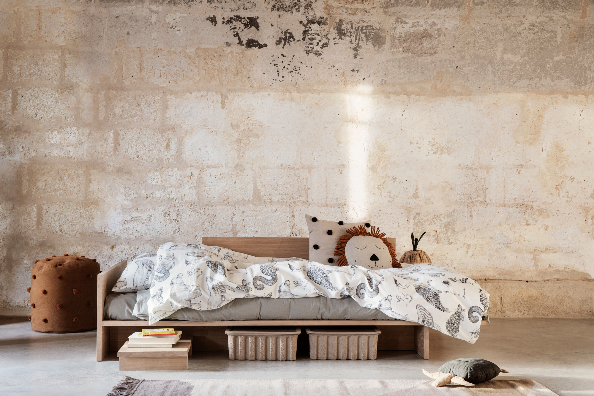 Kona Bett von Ferm Living: Kinderbett aus Holz mit Tier-Bettwäsche und dekorativen Kissen.