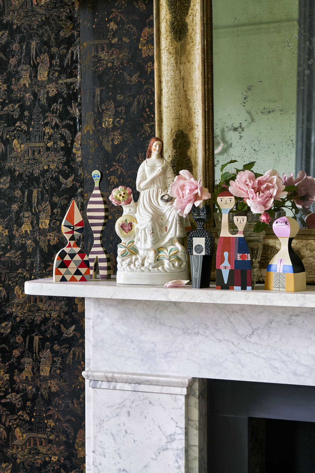 Dekorative Vitra Wooden Dolls Holzfiguren auf einem Marmorkamin, darunter eine Katze, als Wohnaccessoires.